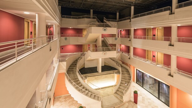 Un atrium à plusieurs niveaux, doté d’un escalier central, de rampes et d’un ascenseur en verre.