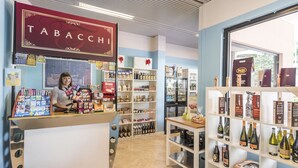 Un magasin de tabac dont les étagères sont remplies de divers produits, un comptoir où sont exposés des articles de tabac, et une vitrine donnant sur l’extérieur.