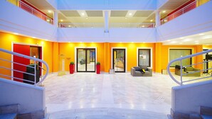 Un hall d’entrée spacieux avec un plafond haut, de nombreuses portes donnant accès à différentes zones et un escalier central.