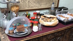 A buffet table with various food items, a map on the wall, and a decorative wooden cabinet. - Bed and Breakfast Coupure (Bruges)