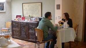Un comedor con un armario de madera, sillas de mimbre y una mesa preparada para dos.