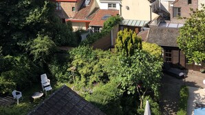 A residential area with terracotta-tiled roofs, a church spire in the background, and a garden with outdoor furniture. - Bed and Breakfast Coupure (Bruges)