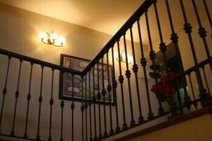 Una escalera con barandilla negra y una lámpara fijada a la pared.