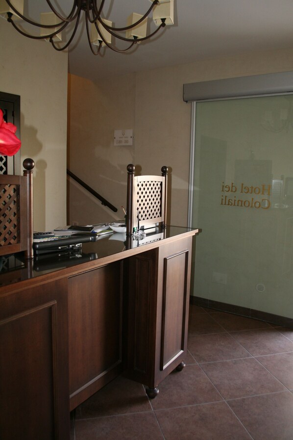 A wooden counter with a chair, a chandelier, and a sliding glass door with a sign.