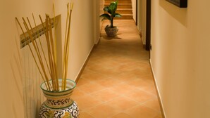 A hallway with a decorative vase, framed pictures, and a potted plant. - Portanova (Naples)
