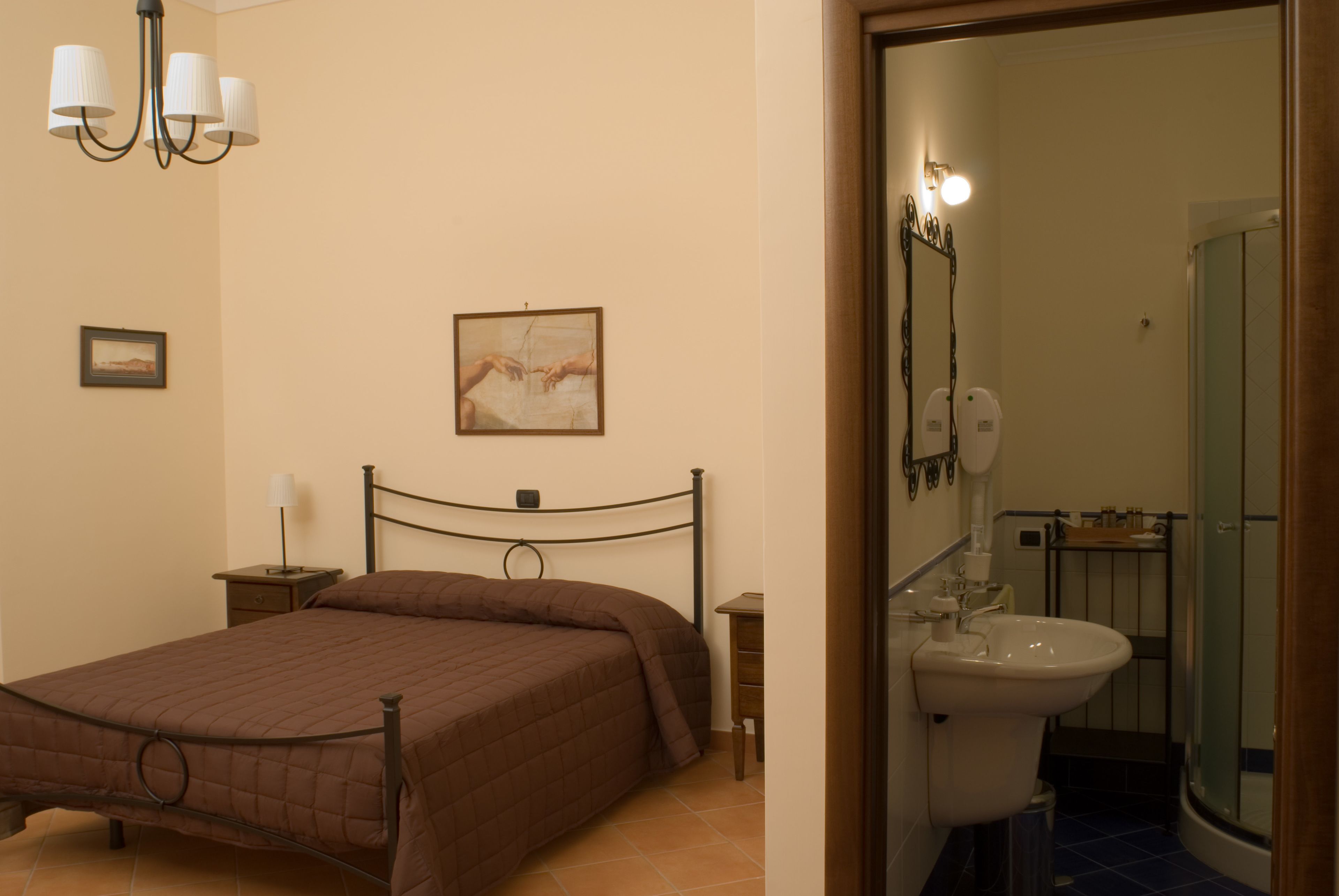 A bedroom with a bed, bedside table, lamp, and a painting on the wall.