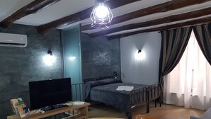 A room with a bed, a TV, a desk, and a dining table. - Portanova (Naples)