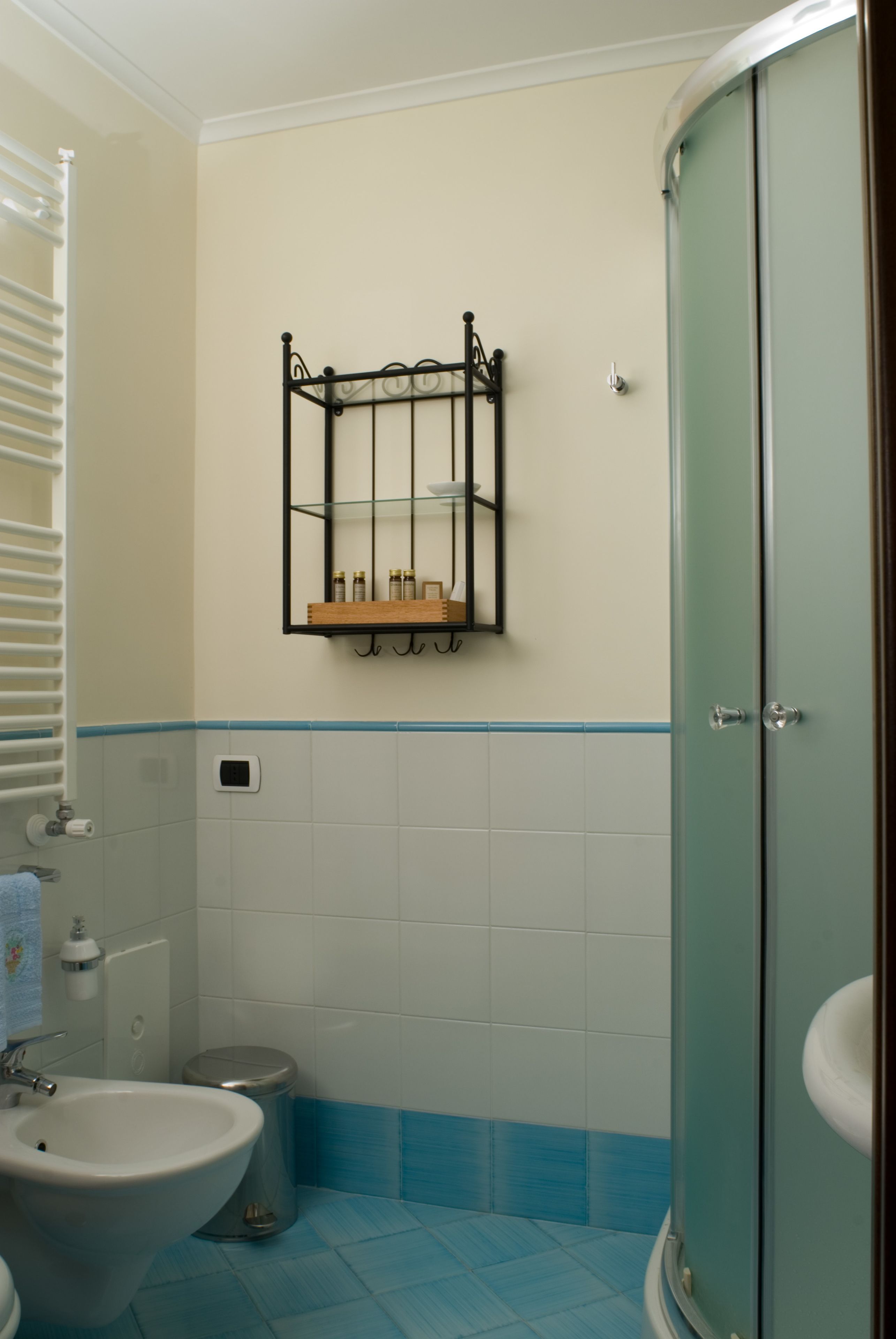 Une salle de bain comprenant des toilettes, un bidet, un lavabo et une douche fermée par une paroi de verre.