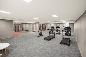 A modern fitness room with exercise equipment, a treadmill, an elliptical, and a stationary bike. - Junshan Hotel (Guangzhou)