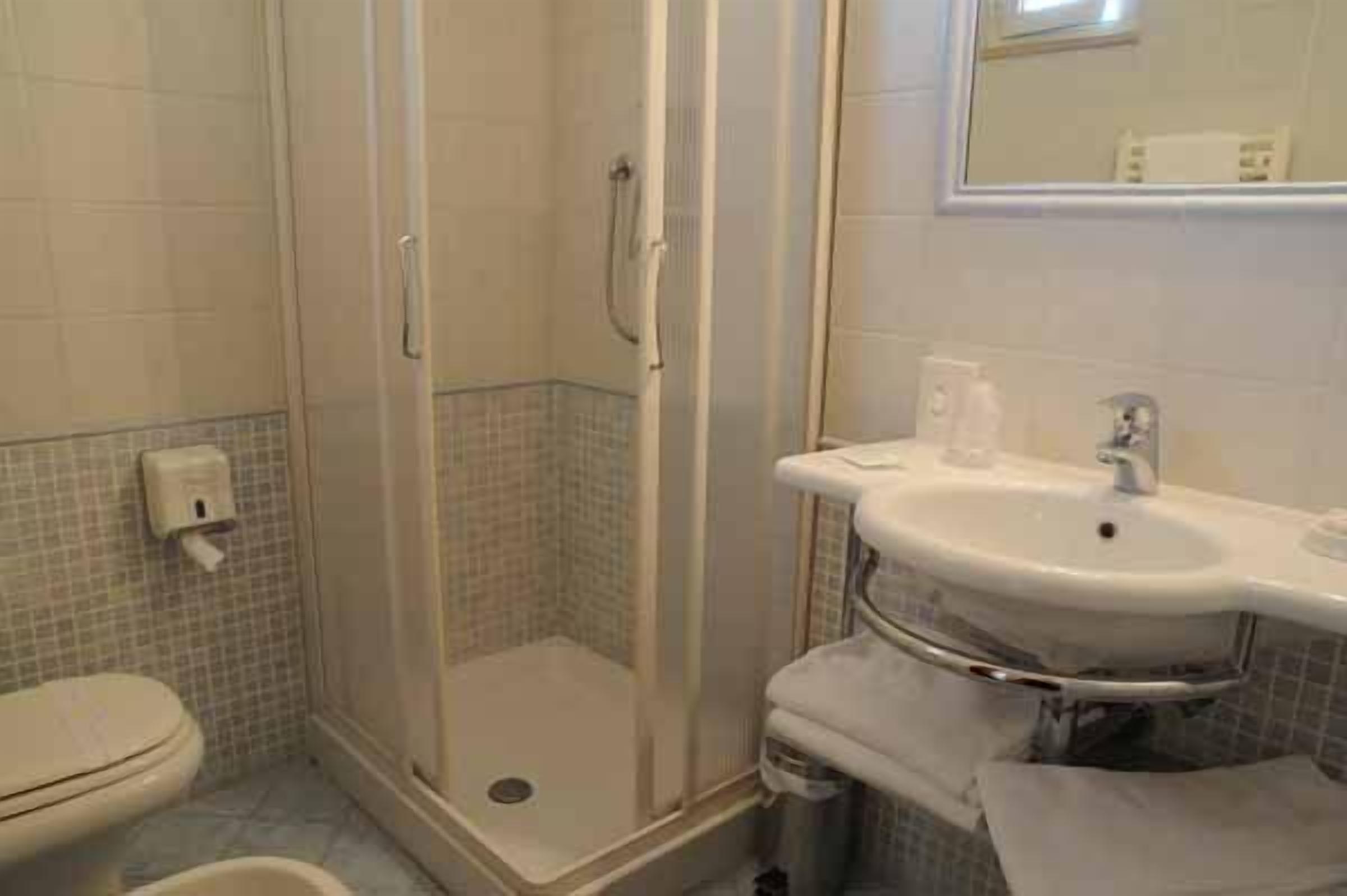 Ein Badezimmer mit Toilette, Duschkabine und Waschbecken mit Spiegel darüber.