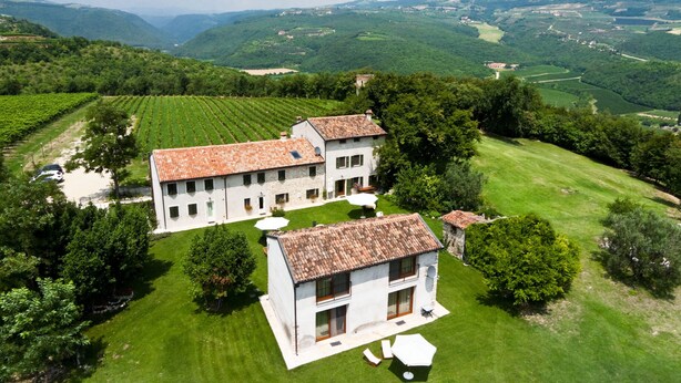 A large white building with a tiled roof surrounded by lush green fields and vineyards. - Tenuta Delo Relais (Verona)