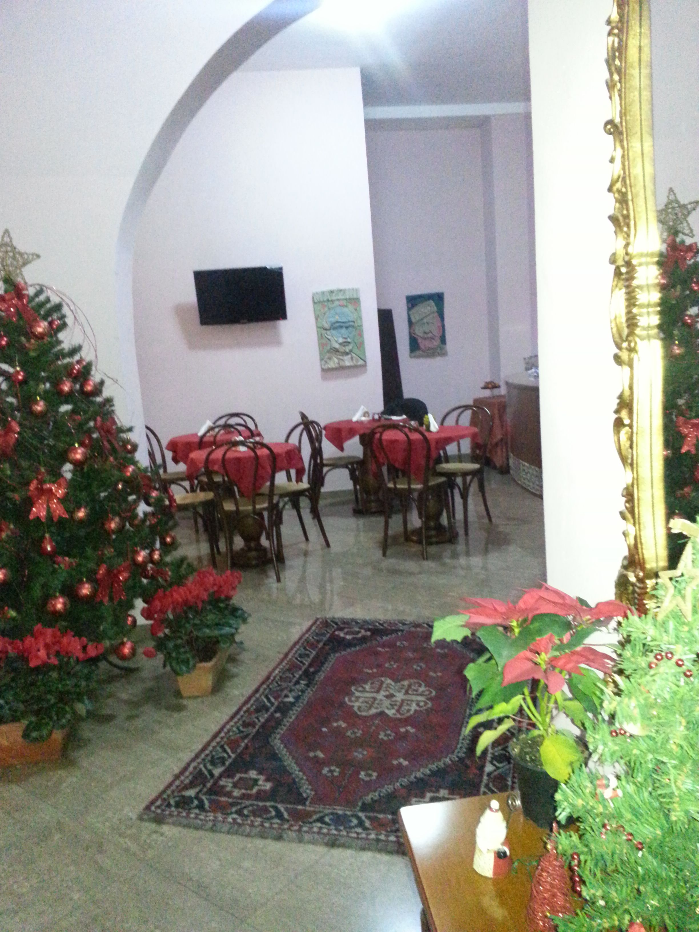 A dining area with tables and chairs, a Christmas tree, and a large mirror.