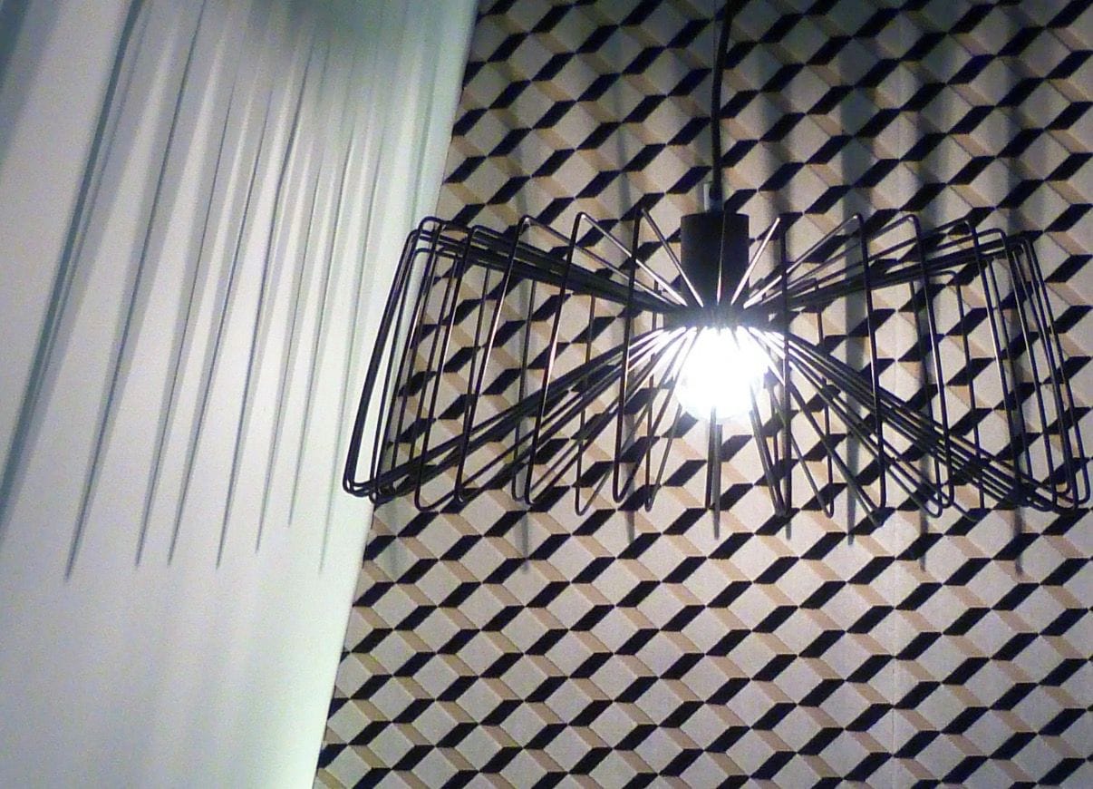 Una parete con motivi geometrici e un lampadario in metallo.
