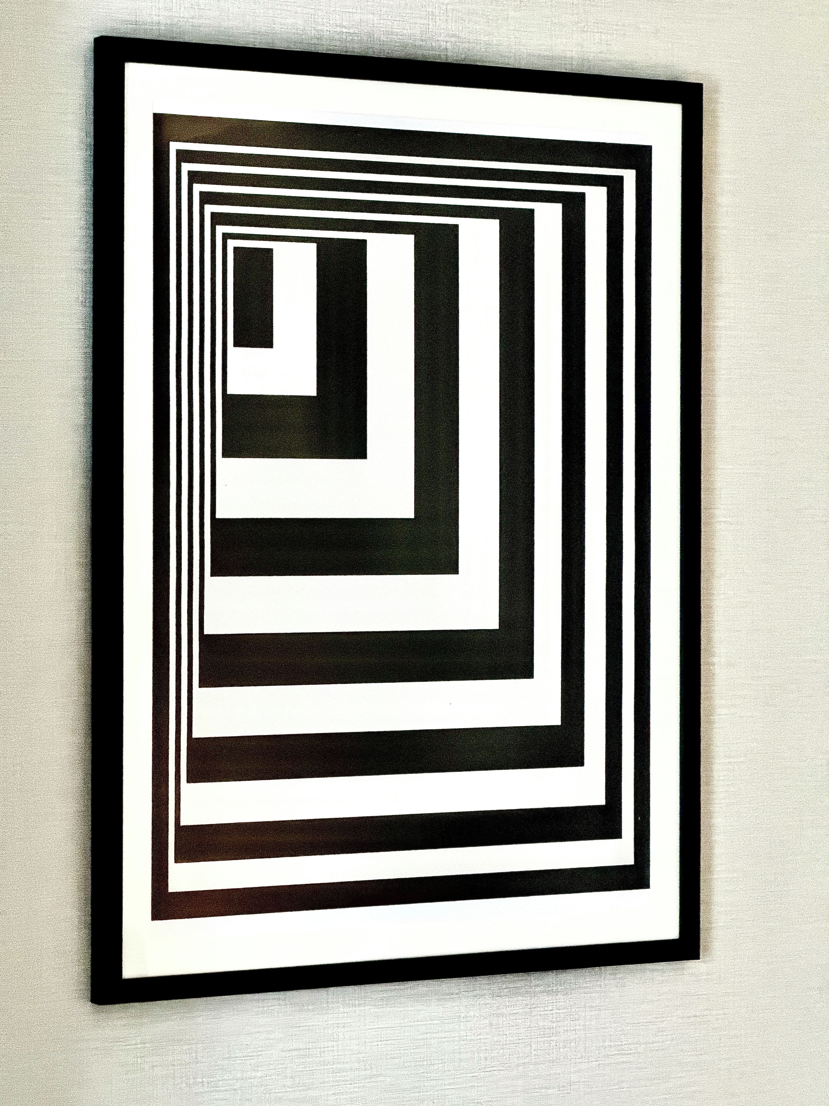 A framed abstract art piece with concentric square patterns.