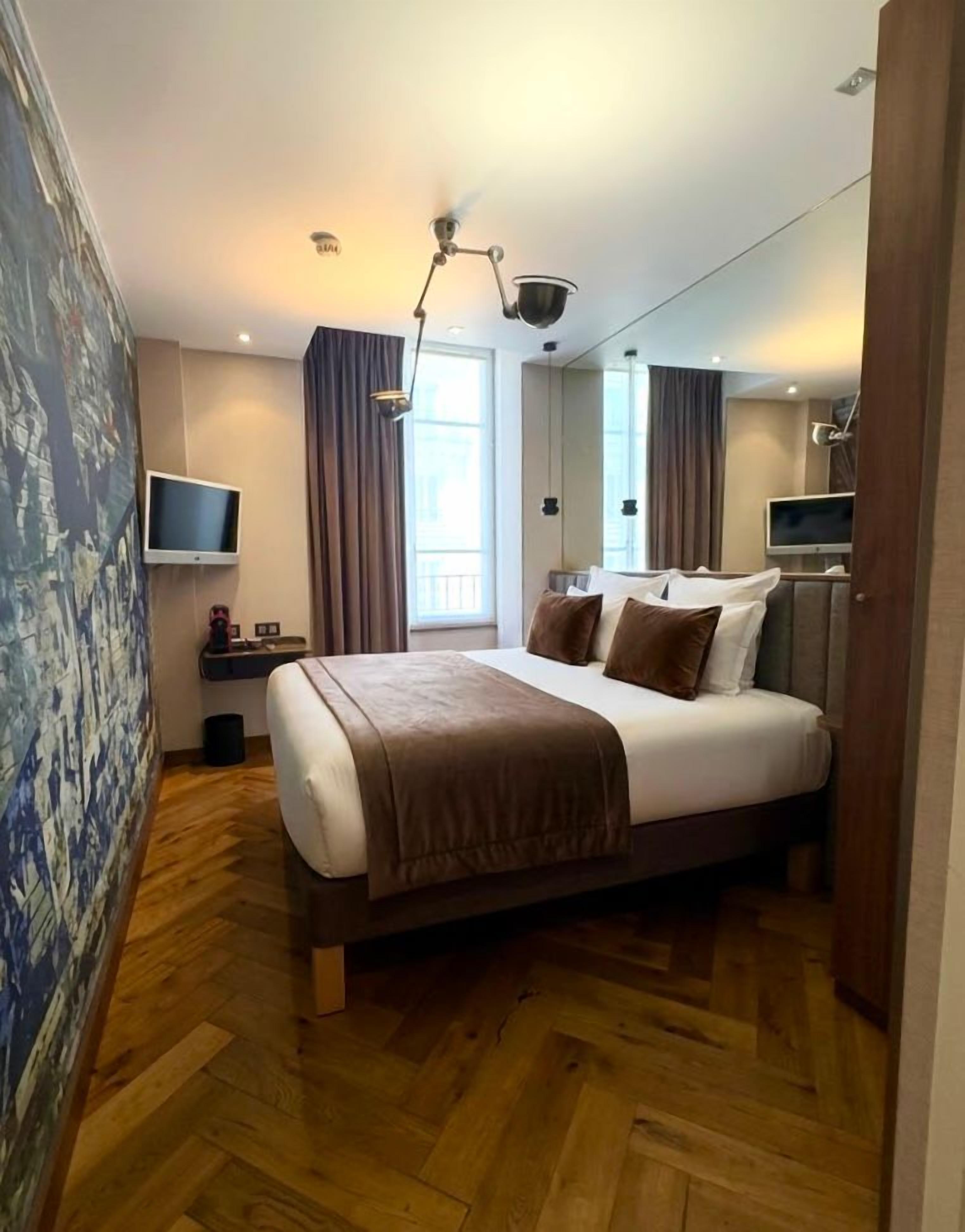Una habitación de hotel moderna con una cama grande, un televisor de pantalla plana, un escritorio y una ventana con cortinas.