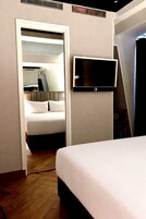 A hotel room with a bed, a television mounted on the wall, and a walk-in closet.