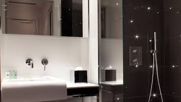 Un baño moderno con ducha envuelta en vidrio, un lavabo blanco y un espejo.