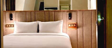 Habitación de hotel con cama, espejo y piso de madera.