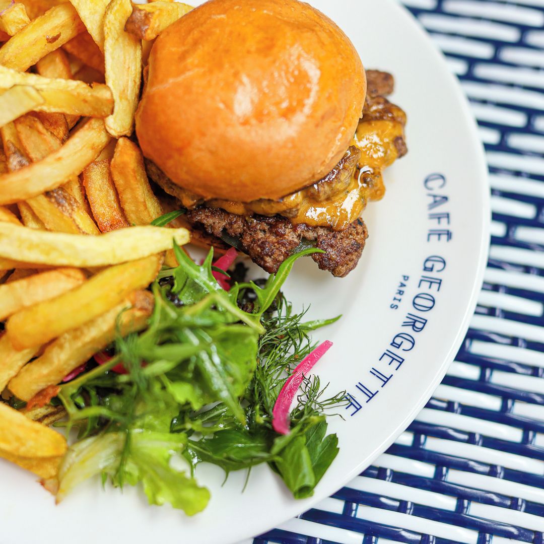 A plate with a burger, fries, and a side salad.