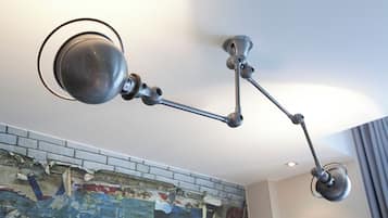 A modern ceiling-mounted lamp fixture with a spherical light and a flexible arm.