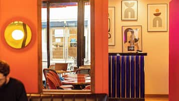 Interior de un restaurante con zona de cabinas, una barra con fondo a rayas azules y obras de arte enmarcadas en las paredes.