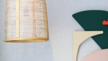 Una lámpara colgante con diseño tejido y una obra de arte en la pared con formas geométricas.