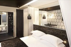 A modern bedroom with a large bed, a vanity with a mirror, and a chandelier. - Hôtel Georgette (Paris)