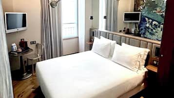 Ein Hotelzimmer mit einem großen Bett, einem Schreibtisch mit Stuhl, einem Fernseher und einem Bild an der Wand.