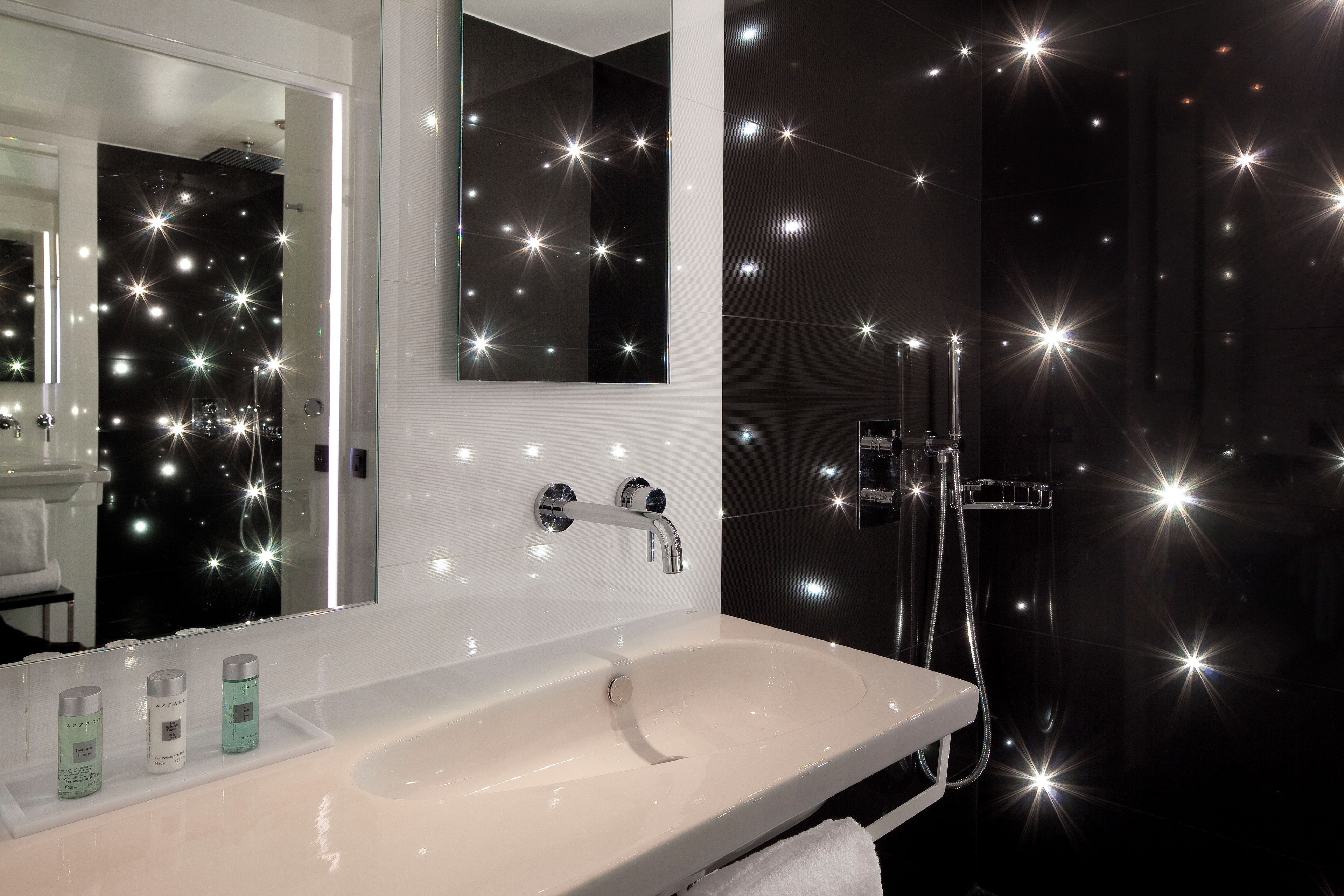 Une salle de bain avec un lavabo blanc, un miroir et un espace douche.
