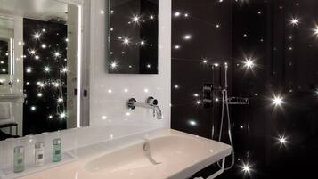 Une salle de bain avec un lavabo blanc, un miroir et un espace douche.