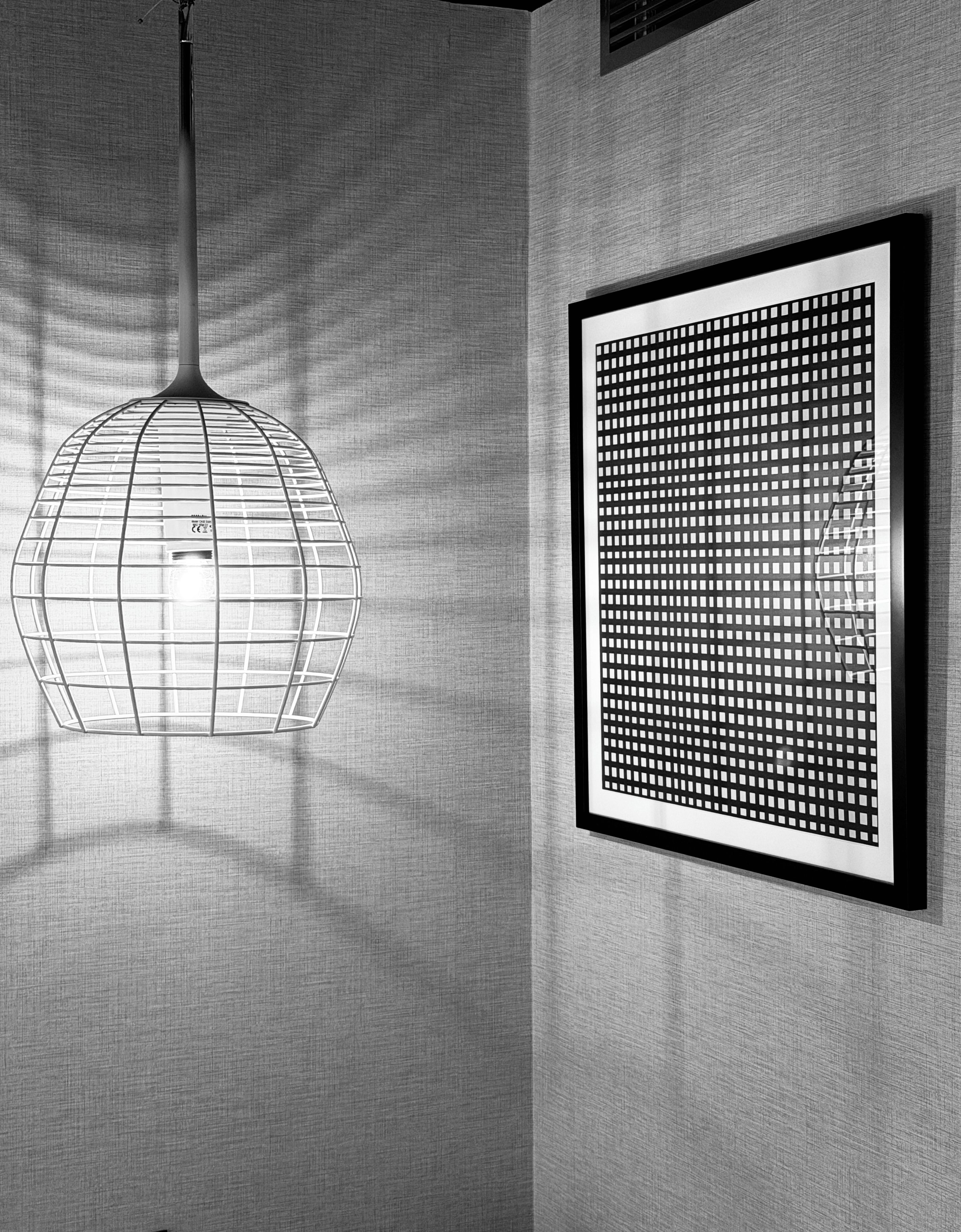 Un intérieur moderne agrémenté d’un luminaire suspendu et d’une œuvre d’art abstraite encadrée au mur.