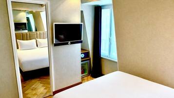 A hotel room with a bed, a TV, a wardrobe, and a window.