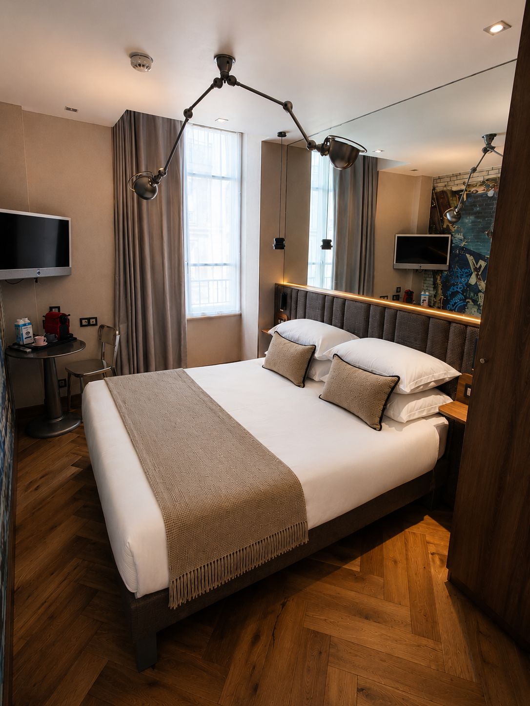 Een moderne hotelkamer met een groot bed, een bureau met stoel, een flatscreen televisie en een groot raam met gordijnen.