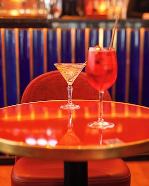 A bar area with a round table, two glasses of drinks, and a striped background.