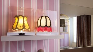 Two illuminated lamps on a shelf against a striped wall. - Hôtel Georgette (Paris)