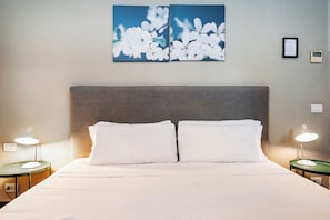 Een hotelkamer met een bed, twee nachtkastjes, een wanddecoratie en een ingelijst certificaat.