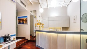 Un espace d’accueil avec un comptoir, un tableau encadré au mur, un vase avec des fleurs et une horloge.