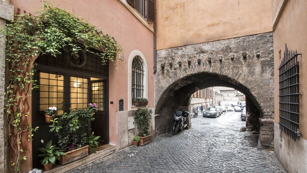 A narrow cobblestone street with a stone archway, potted plants, and a parked motorcycle. - Arco del Lauro Bed & Breakfast (Rome)