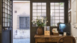 A room with a wooden desk, a vase with flowers, a television, and a chair. - Arco del Lauro Bed & Breakfast (Rome)
