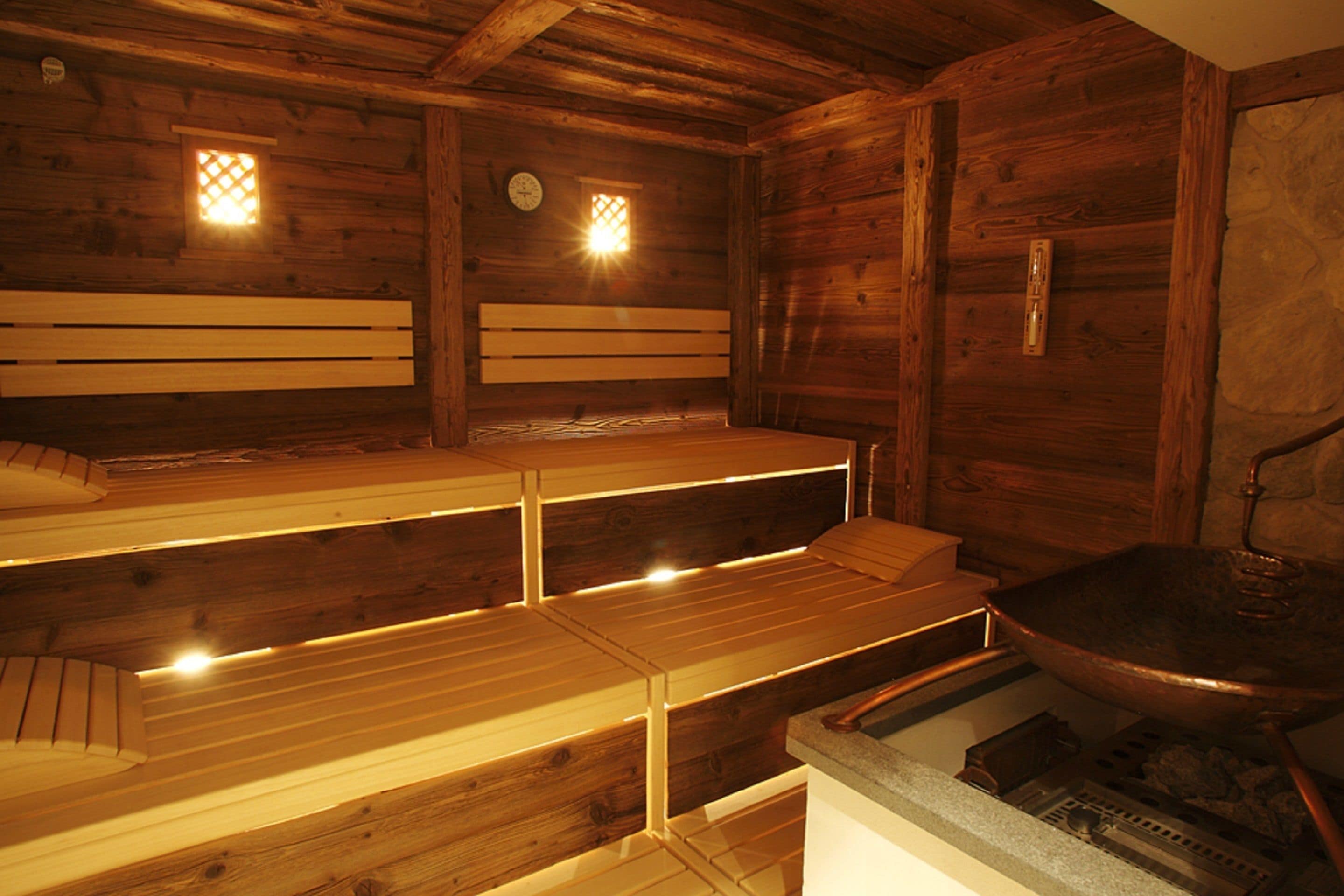 Una sauna de madera con bancos y un lavamanos de piedra.