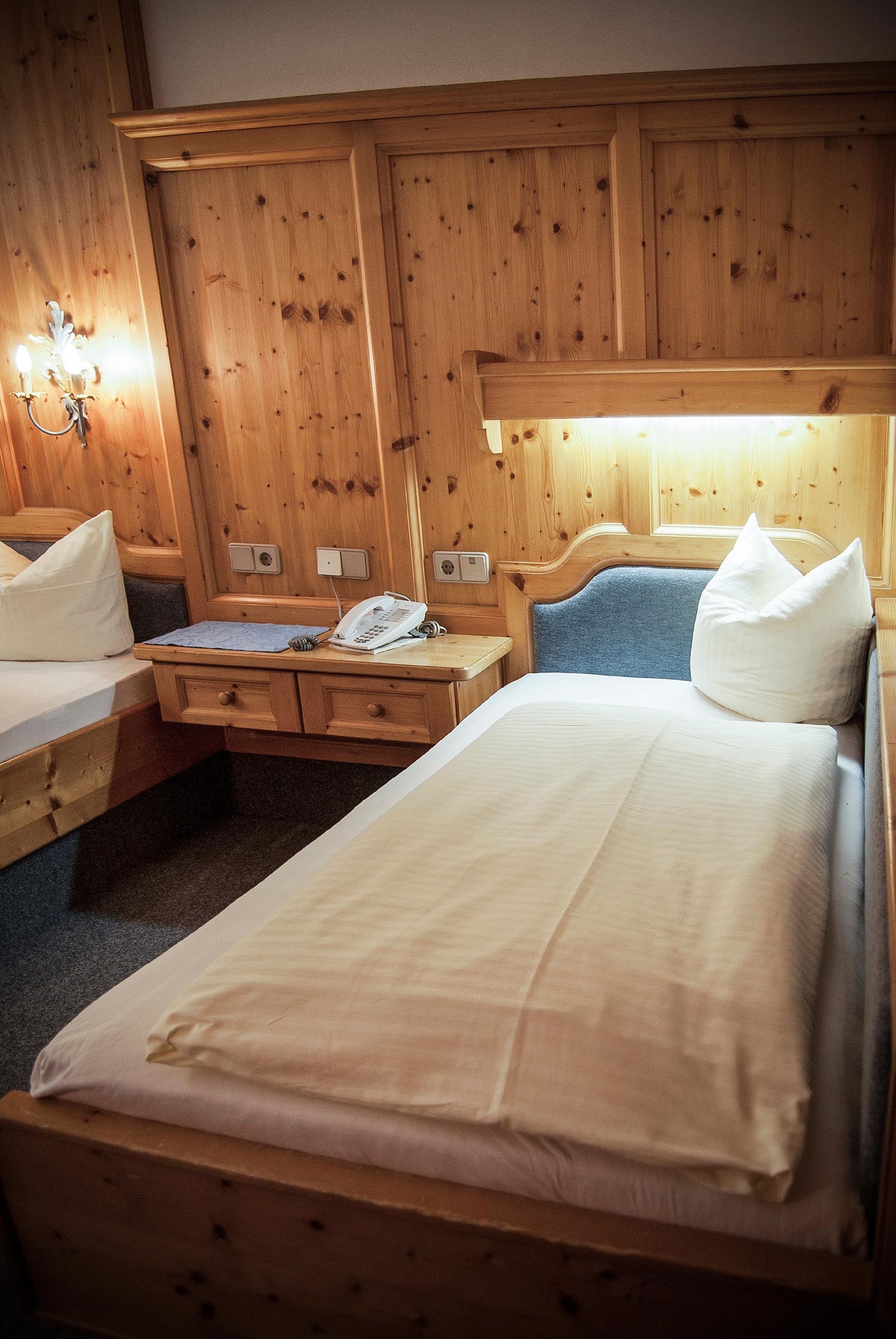 Una habitación tipo cabaña de madera con dos camas, un escritorio y una mesita de noche.