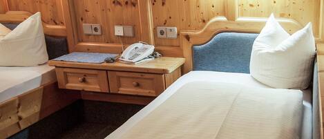 A wooden cabin-style room with two beds, a desk, and a nightstand.