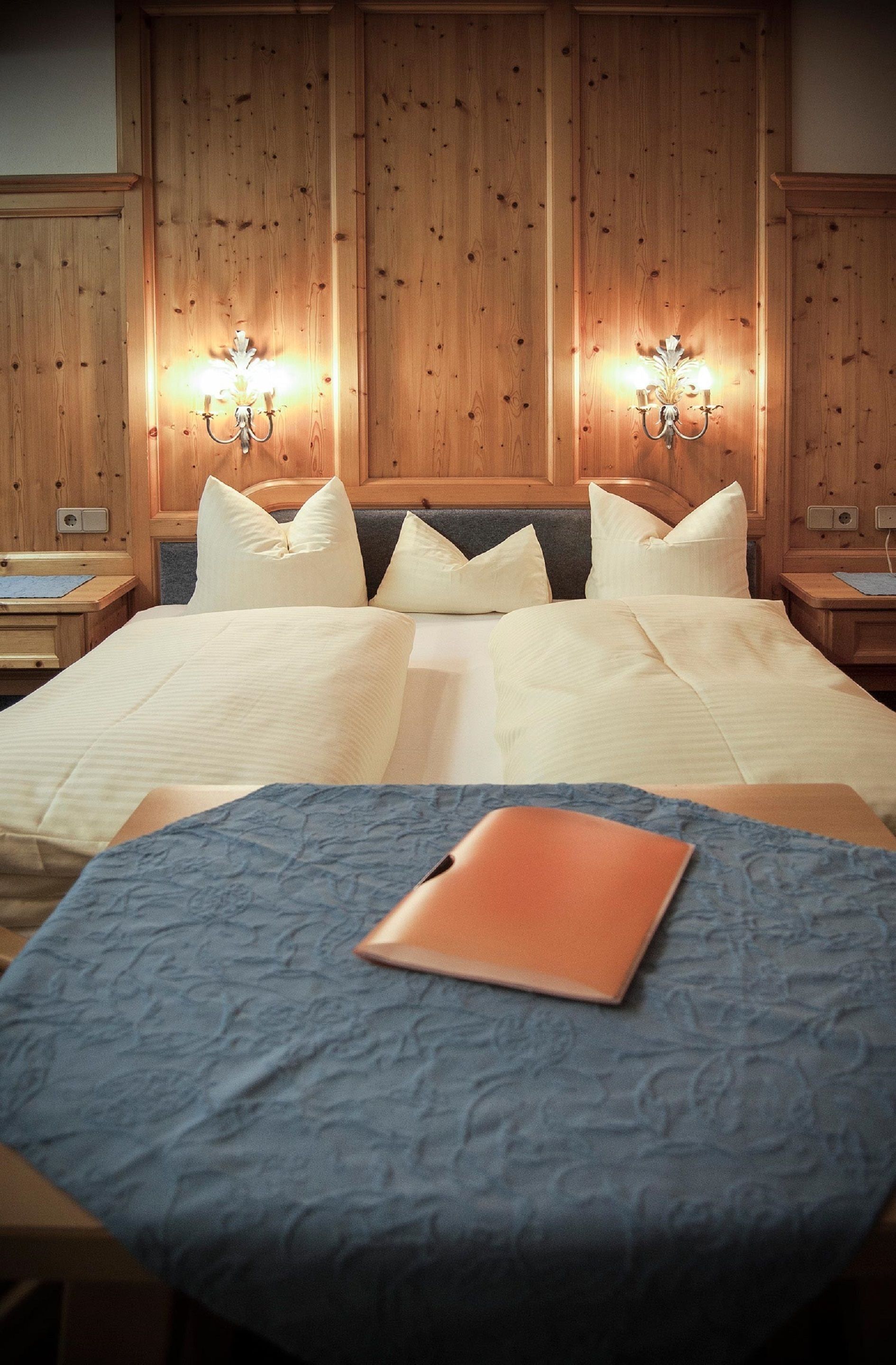 A hotel room with a large bed, two bedside tables, and wall-mounted lamps.