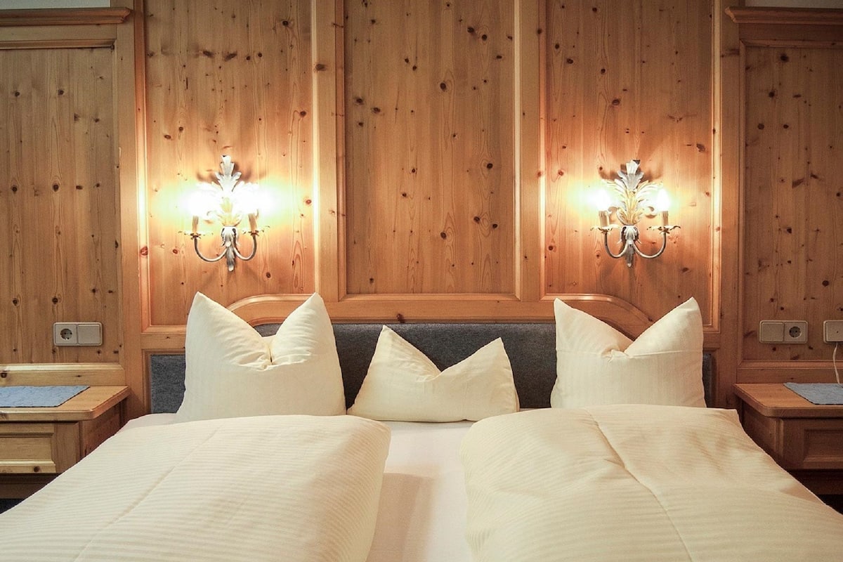 A hotel room with a large bed, two bedside tables, and wall-mounted lamps.