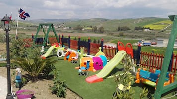 Children can play and climb in the secure fenced play area with slides and climbing frames.