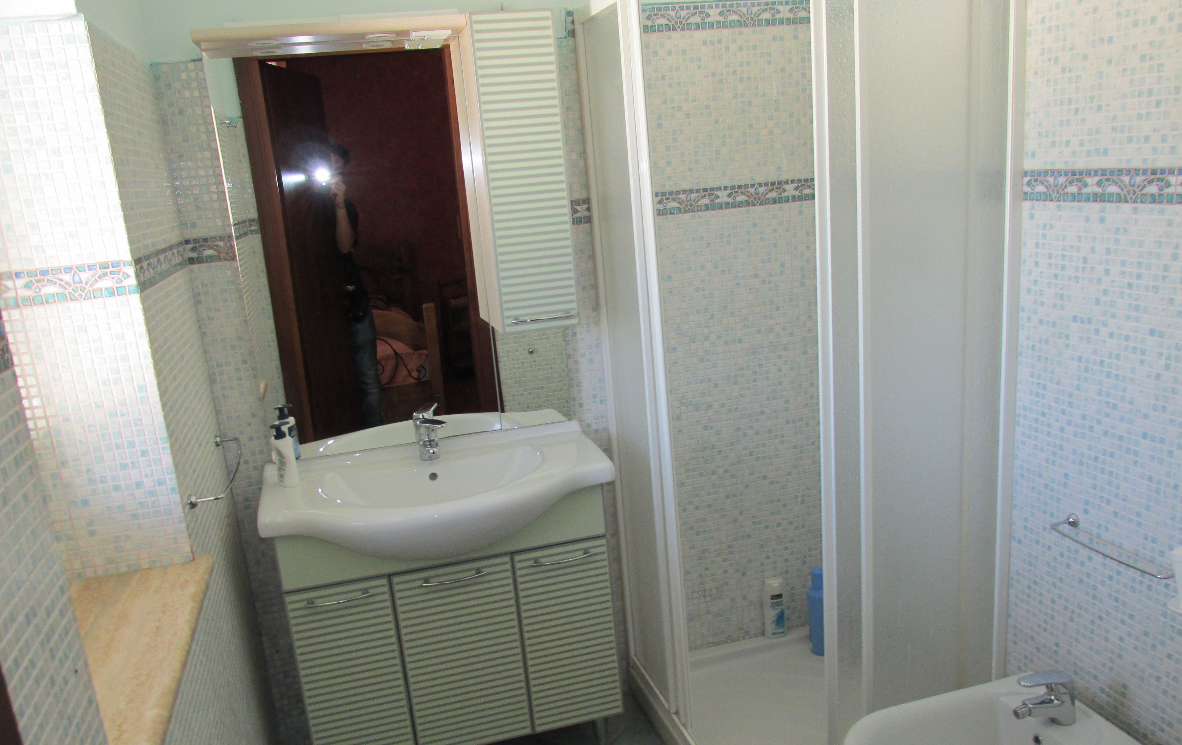 Un bagno con lavabo, specchio e zona doccia.