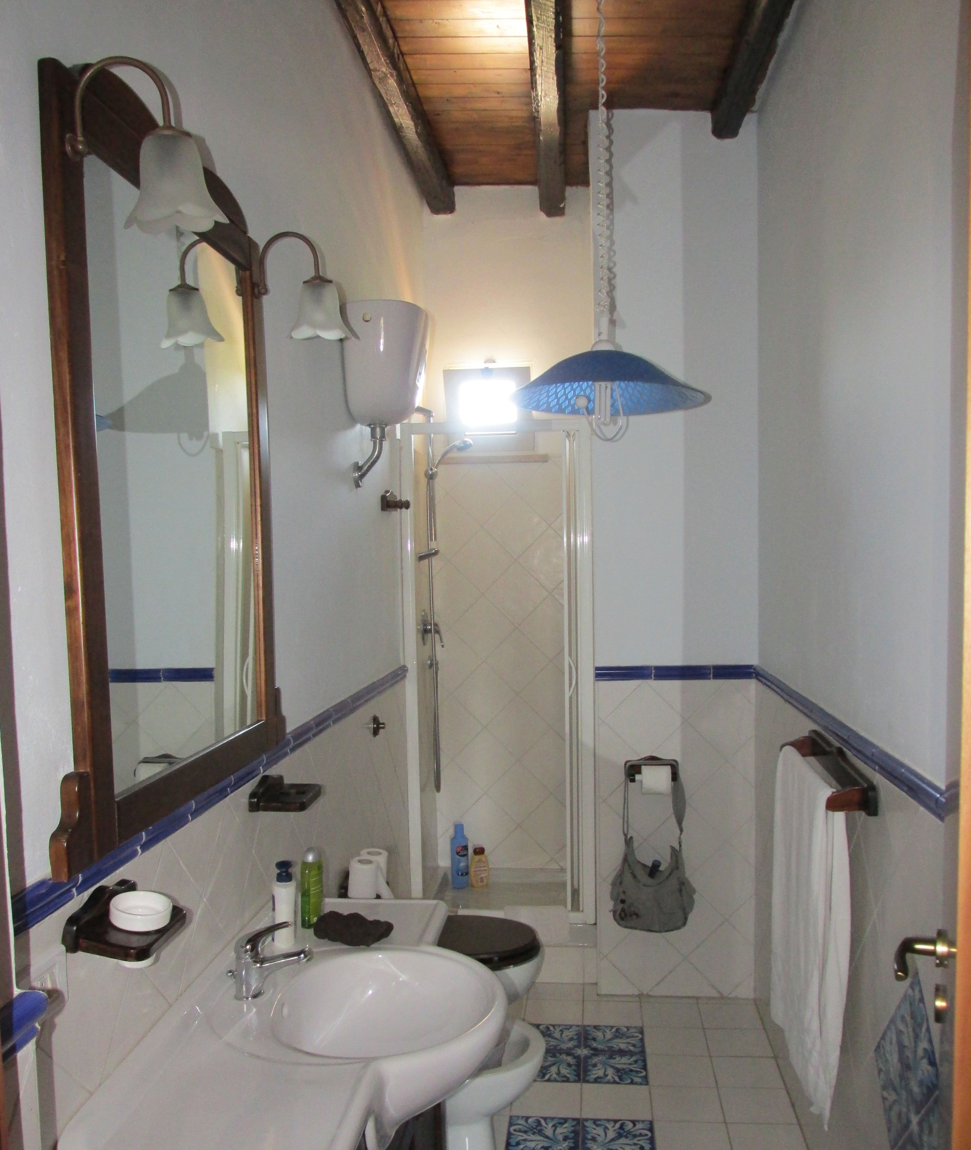 A bathroom with a sink, mirror, shower, and towel rack.