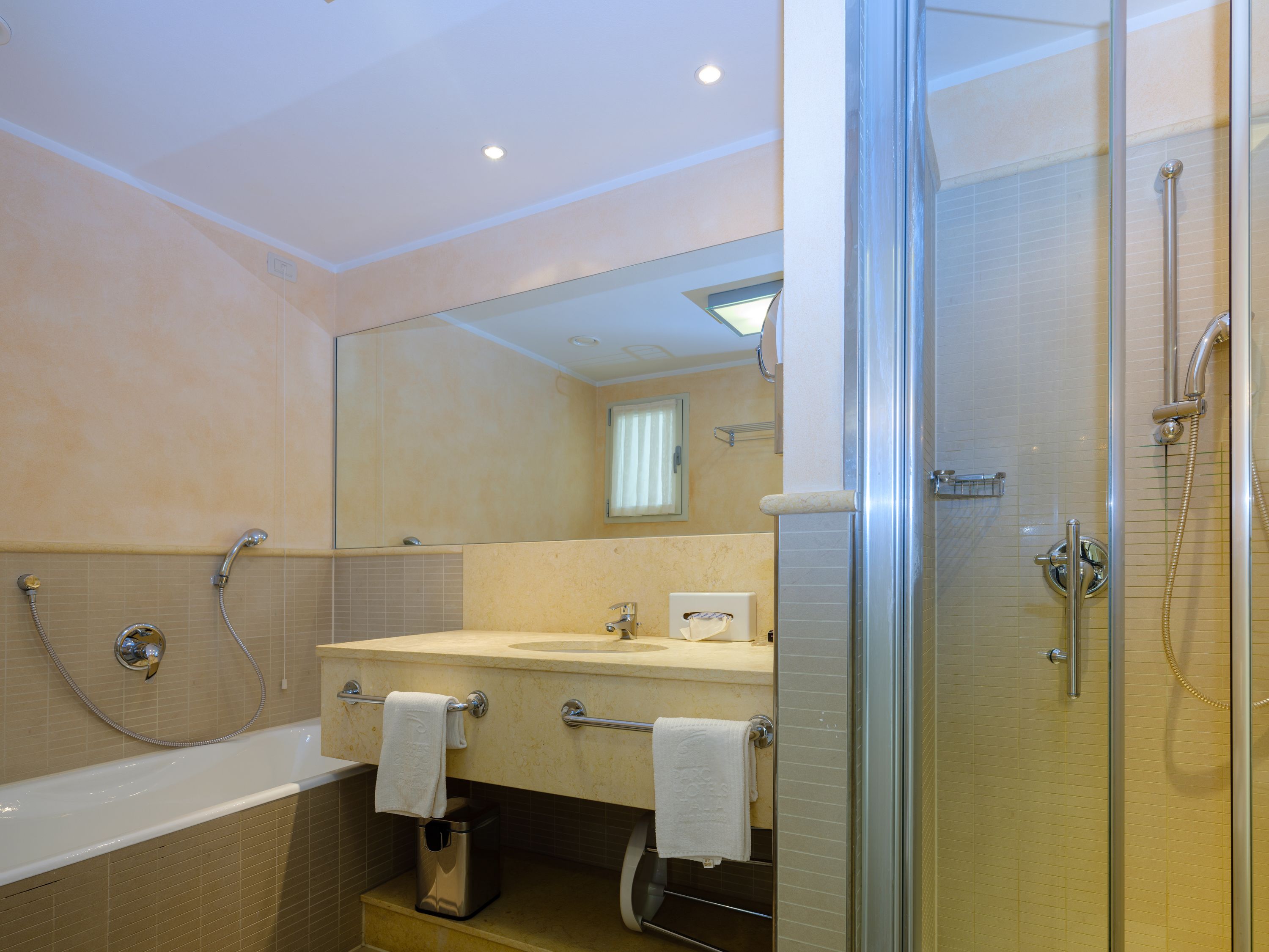 A modern bathroom with a glass-enclosed shower, a bathtub, and a vanity with a mirror.