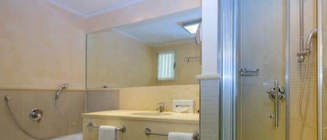 A modern bathroom with a glass-enclosed shower, a bathtub, and a vanity with a mirror.