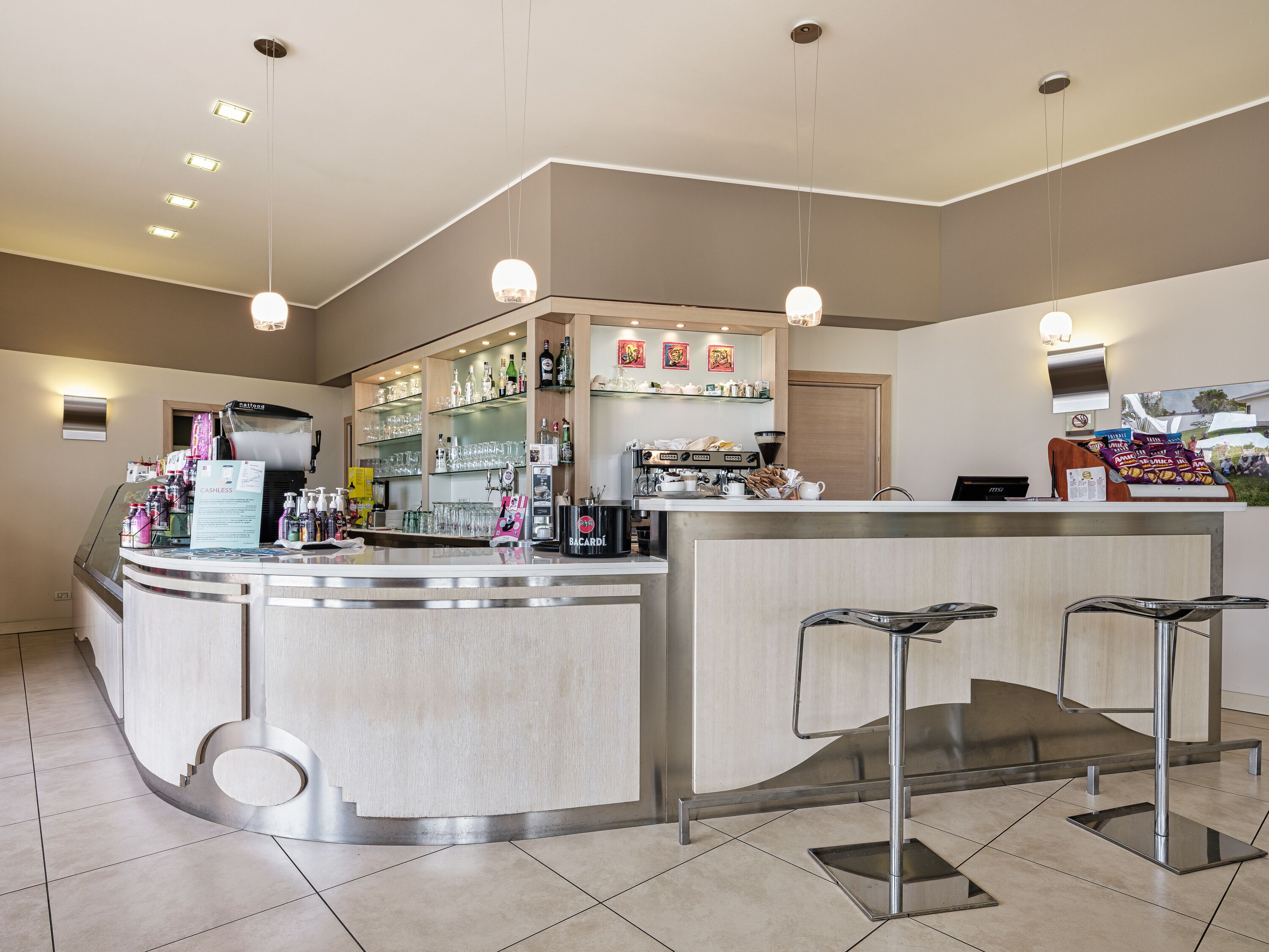 A modern bar area with a cashless payment option, a coffee machine, and a variety of beverages and snacks.